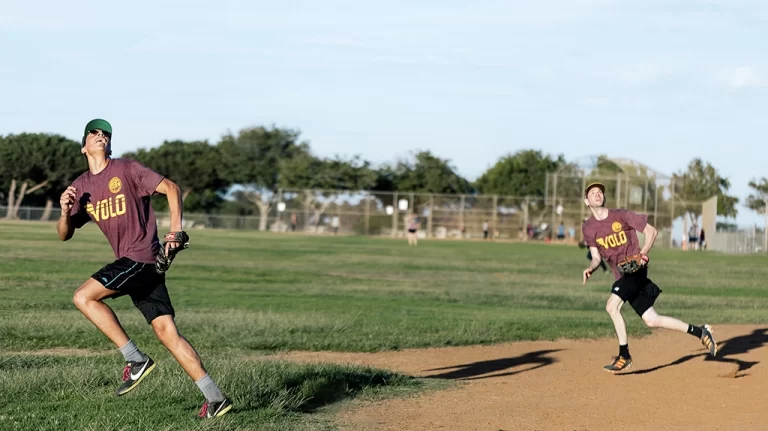 2 people catching a softball during an adults sports softball league game